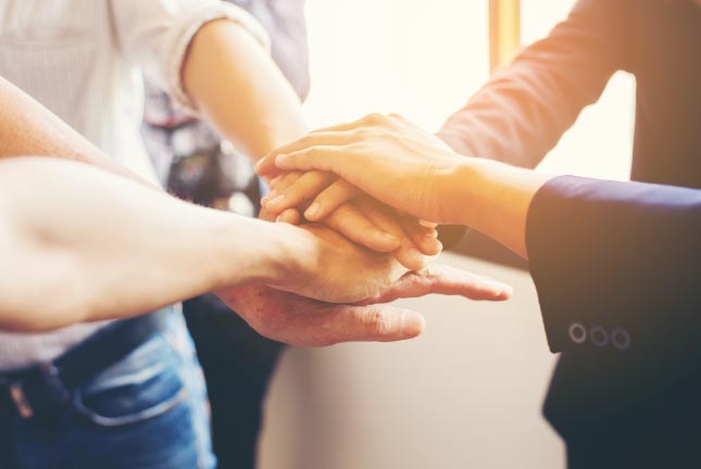 group of business people with hands stacked in middle to show team work